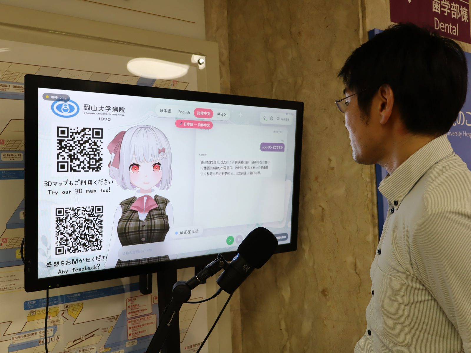 岡山大学病院に設置された生成AIアバター案内サイネージに、来院者が話しかけている様子
